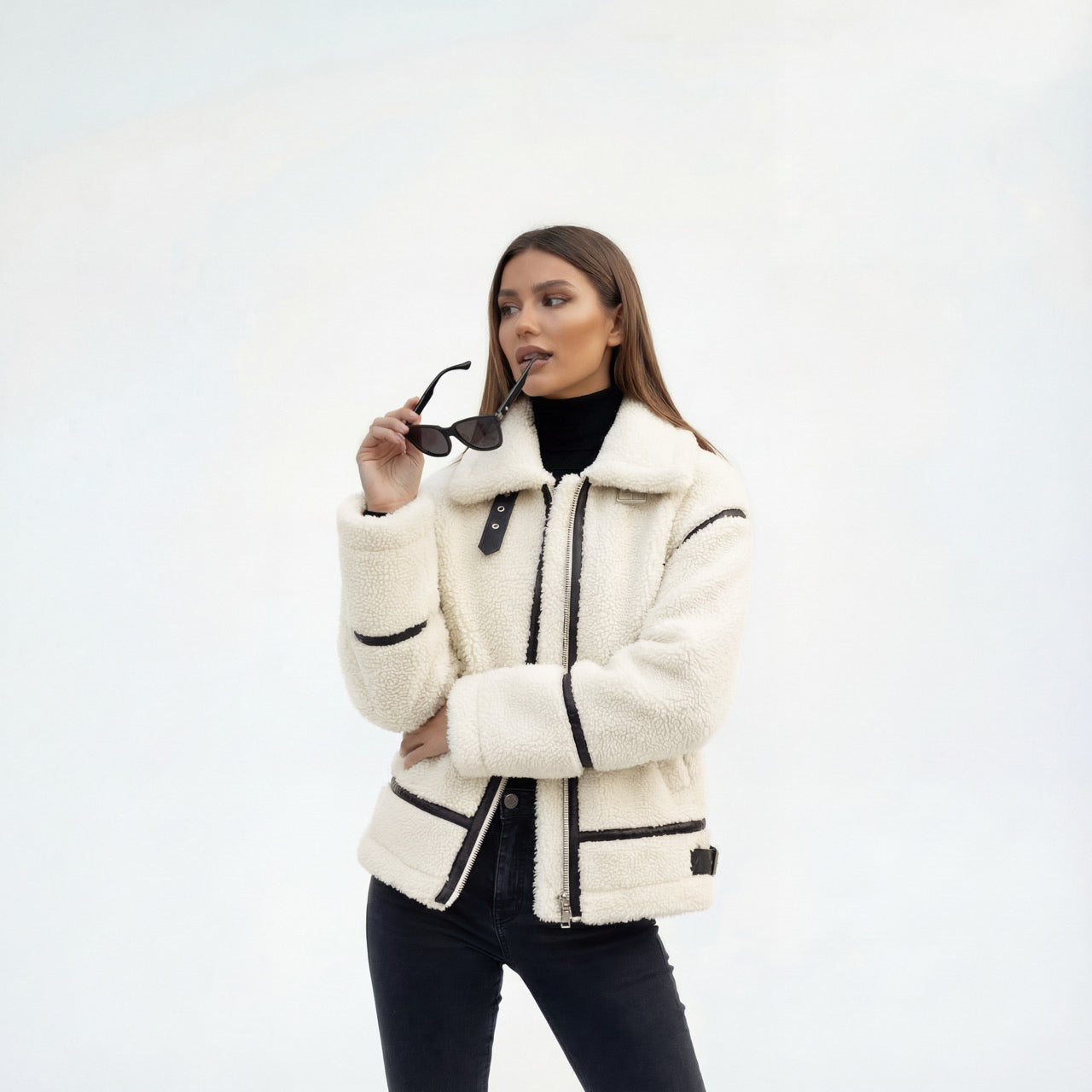 Woman wearing a white sherpa jacket on a light gray background